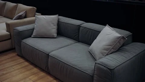 Gray sofa with two pillows filmed in a furniture store, in the background there Stock Footage 233379618