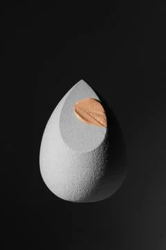 Gray sponge on a black background with tonal cream. Foto stock