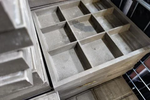 Gray square molds stacked in a workshop showcasing various compartments for Stock Photos