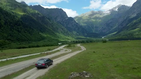Gray station wagon moving on dirt road in mountain valley 스톡 동영상 301233359