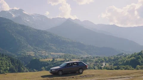 Gray station wagon parked meadow overlooking picturesque valley mountain range 库存影片 301403071