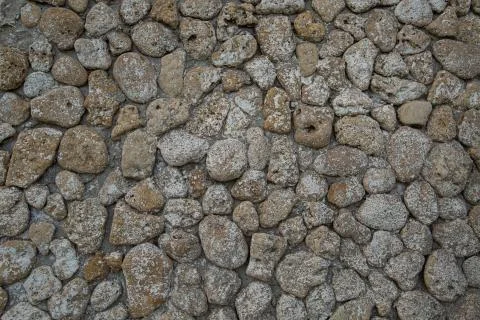 Gray stone wall background, rounded beige stones Stock Photos