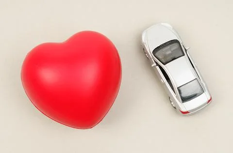 On the gray surface are the heart and the car model. Stock Photos
