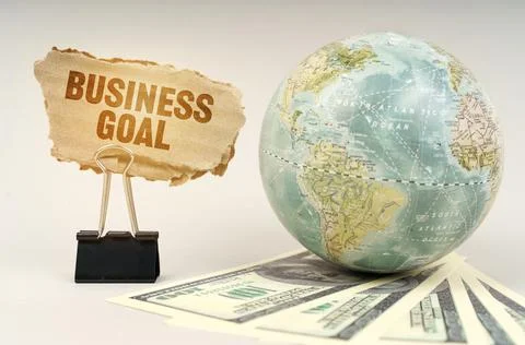 On a gray surface, a globe, dollars and a cardboard plate with the inscriptio Fotos de archivo