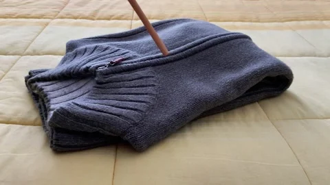 Gray Sweater Neatly Folded on Soft Yellow Surface Stock Footage 322510068