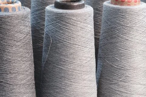 Gray thread spools are positioned side by side. Thread is tightly wound aroun Stockfoto's