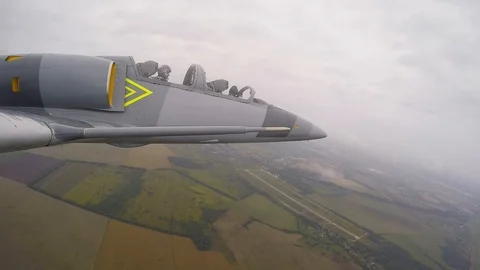 Gray training plane fly over fields and rolls to left. right Wing view close up. Stock Footage 118676645