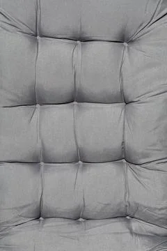 Gray tufted upholstered cushion surface with stitched square textile pattern Stockfoto's