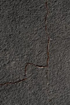 Gray wall with a crack. Texture of rough plaster with uneven granular coating Stock Photos