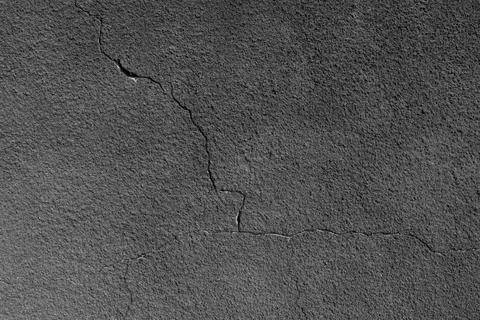 Gray wall with a crack. Texture of rough plaster with uneven granular coating Foto stock