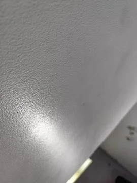 Gray wall displays a textured surface with glossy finish, captured in a close Фото