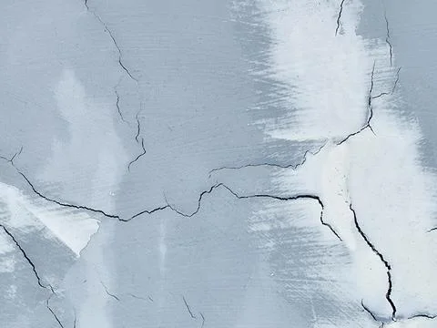 Gray wall with multiple cracks and patchy repair marks Stock Photos