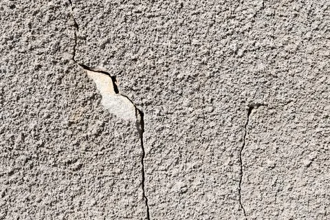 Gray wall on which the plaster cracked and a piece chipped off, texture Stock Photos