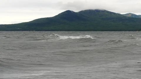 Gray waves against the background of low mountains in inclement weather. Stock Footage 290119457