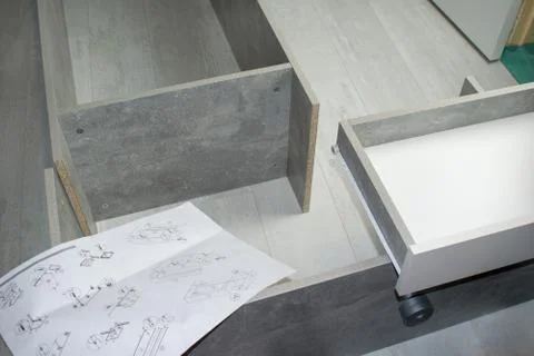 Gray wooden wardrobe. Components for assembling a new cabinet on the floor. B Stock Photos