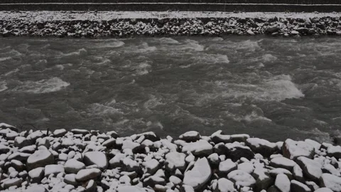 Grayscale image depicting fast flowing river with rocky shoreline Video stock 333335564