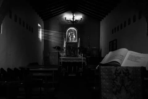 Grayscale inside a church building with an opened book in front and icons in the Fotos de archivo