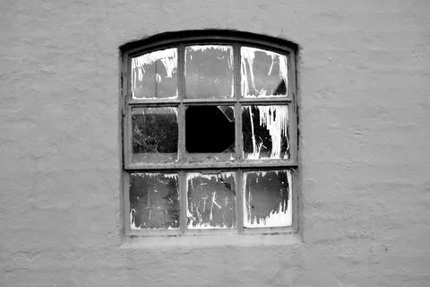 Grayscale shot of old broken windows of an abandoned building in the daylight Fotos de archivo