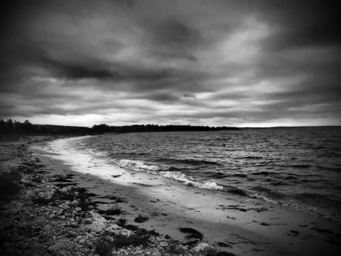 Grayscale shot of the seashore under a brooding sky Stock Photos