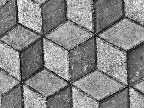 A grayscale tiled surface shows interlocking hexagonal paving stones with tex Stock Photos