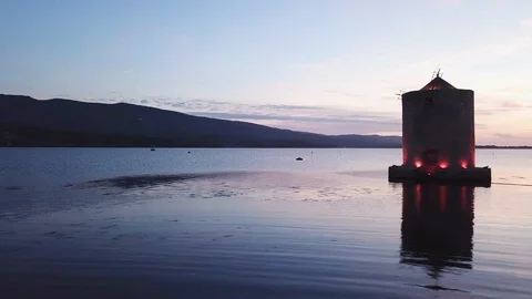 Grazing flight around A romantic windmill on a calm sea lagoon at dusk Stock Footage 107848206