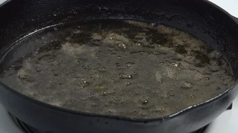 Grease in a Cast Iron Pan Bubbles Up Close on a Kitchen Stove Vidéo 130547856