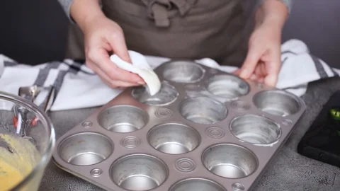 Greasing muffin pan for baking spicy jalapeno cornbread muffins. Stock Footage 97152983