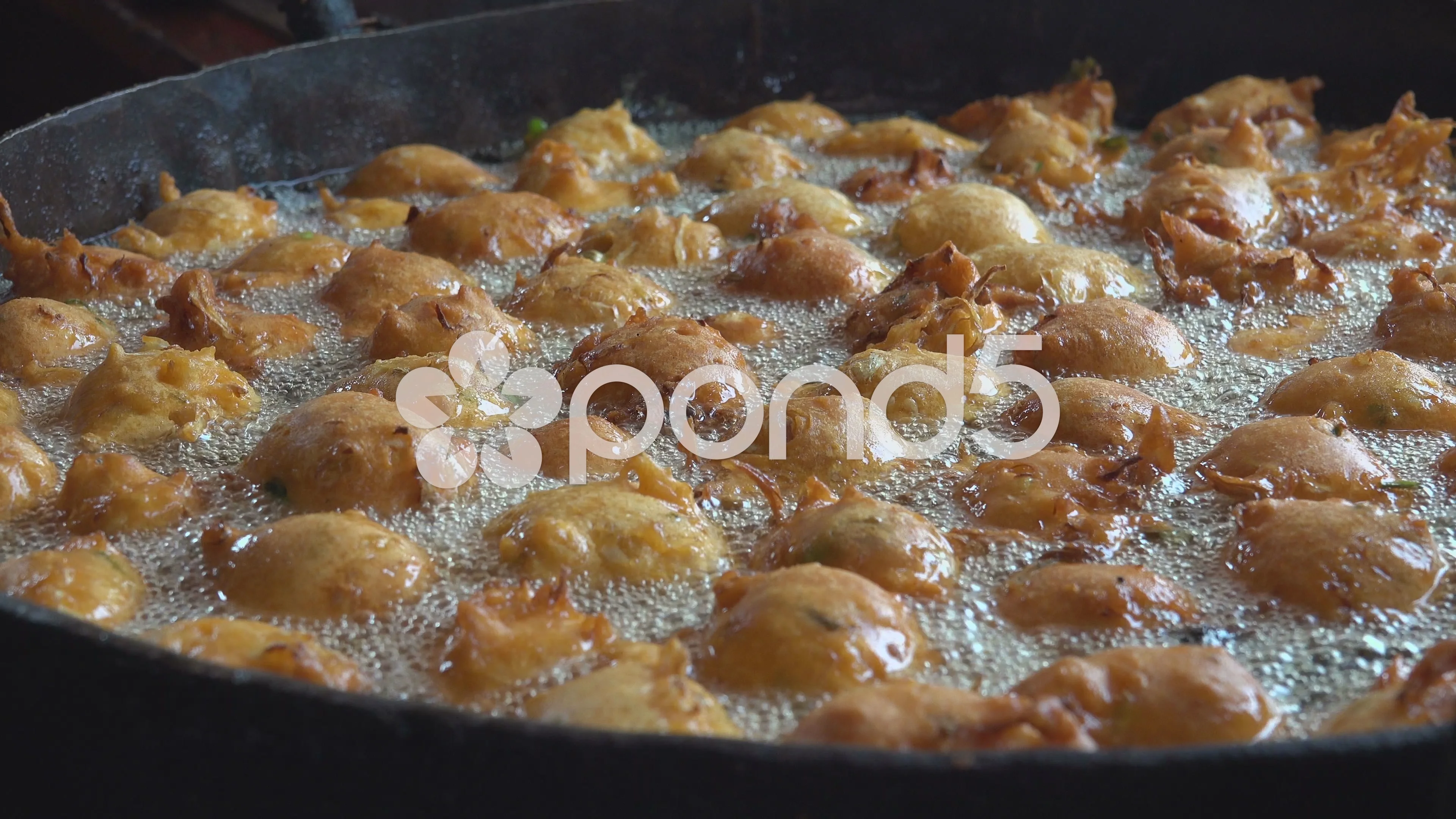 Greasy indian food being stirred in large pan