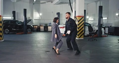 Great day at work mechanic guy and owner of the car a good looking lady dancing Stock Footage 119109039