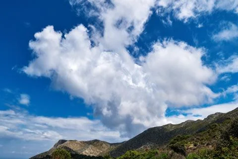Great dynamic clouds in beautiful blue sky over hills and slope at daytime Stock Photos