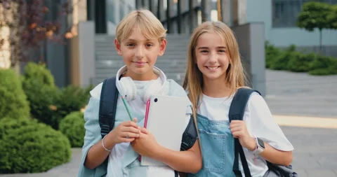 Great elementary school. Happy boy and girl classmates with books and backpack Stock Footage 248614569