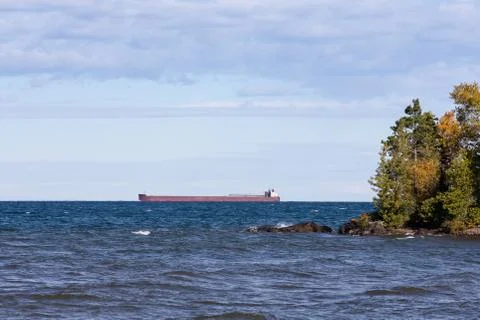 Great Lakes Freighter Passing Behind a Rocky Island Stock Photos