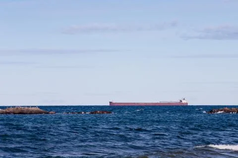 Great Lakes Freighter Passing Behind Rocky Outcroppings Stock Photos