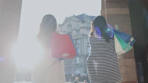 Great shopping. Back view of the two best friends walking through the sunny Stock Footage 156032052
