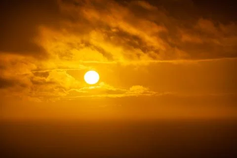 Great sun peeking through the clouds in a golden sunset over the sea, Asturias Stock Photos