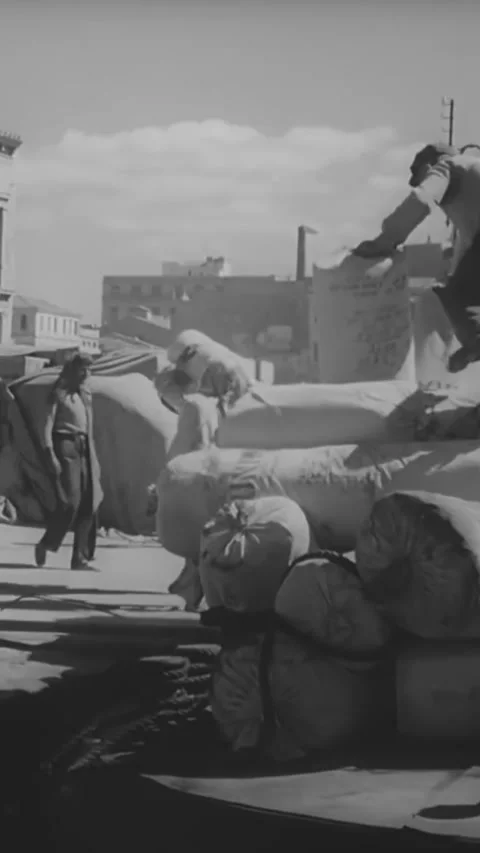 GREECE - 1940s - Men unload cargo from boats in a Greek harbor. Stock Footage 342634439