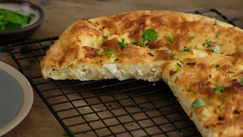 Greek cheese pie. Cuts pie. Slice pie. Woman prepares a pie with feta cheese and Stock Footage 141364057
