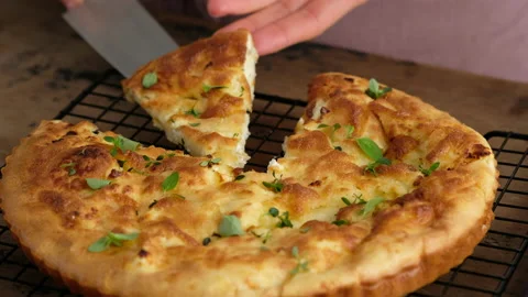 Greek cheese pie. Woman cuts pie. Woman prepares a pie with feta cheese and Stock Footage 141363653