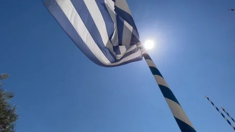 Greek flags waving in the bright sun against a clear blue sky Stock Footage 345259522