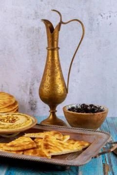 Greek party table with hummus, bread and copper jug. Stock Photos