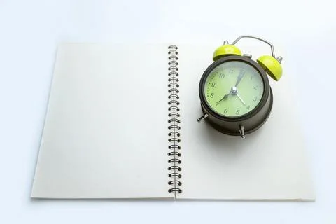 Green alarm clock and notebook on white background. Empty area for mockup o.. Foto stock