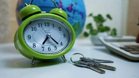 Green alarm clock, keys, globe, and calculator on a desk Stock Footage 317131695