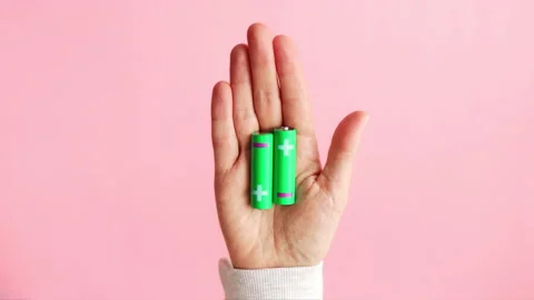 Green alkaline batteries AA type rechargeable accumulators in hand Stock Footage 235470807