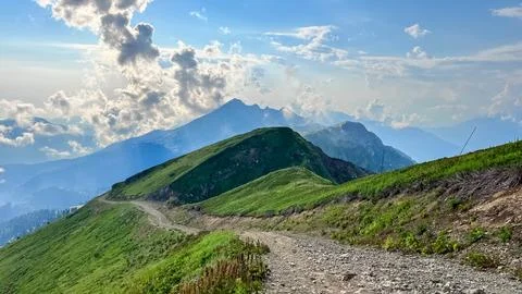 Green Alpine Mountain Trail with Dramatic Mountain Peaks Stock Photos