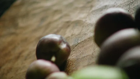 Green and black olives fall towards the camera on wooden floor. Stock Footage 128404867