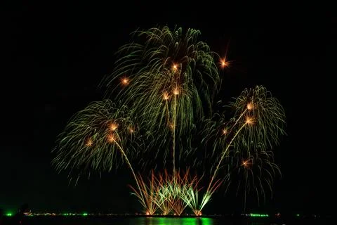 Green And Gold Fireworks Exploding Over Ocean Water In Dark Night Sky Long .. Stock Photos