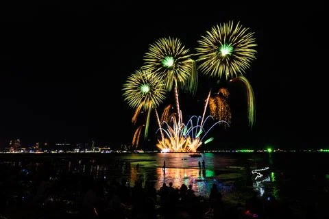 Green And Golden Fireworks Exploding Over Beach At Night Wide Shot Stock Photos