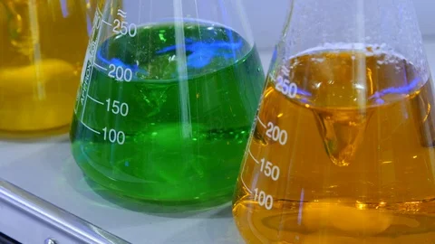Green and orange liquid is mixed by a machine in a laboratory Stock Footage 126717580