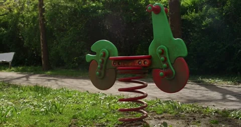 Green and Red Motorcycle Spring Rider on a Coil, Sunny Playground, Wide Shot Stock Footage 340637963