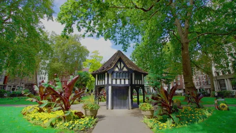 Green and vibrant Soho Square Gardens with walking people in 4K. Stock Footage 139944451